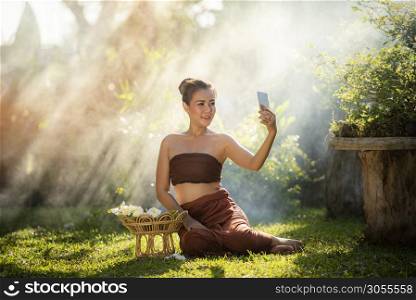 Asia woman smiling young girls taking selfie portrait with smartphone in the garden / Woman drama style dress thai traditional costume wearing