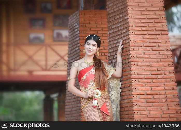 Asia woman thai style dress / Portrait of beautiful young girl smiling Thailand traditional costume wearing with thai jasmine garland in hand