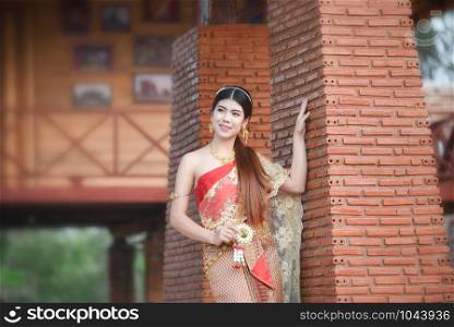 Asia woman thai style dress / Portrait of beautiful young girl smiling Thailand traditional costume wearing with thai jasmine garland in hand