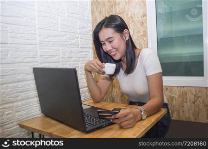 Asia woman using credit card and laotop in cafe