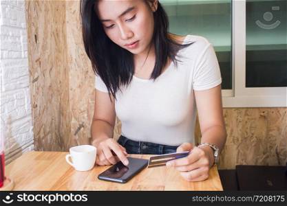 Asia woman using credit card and smart phone in cafe