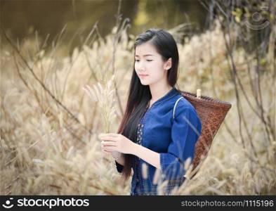 Asia women farmer in grass field nature / Portrait of beautiful asian young girl happy smile with basket for harvest agriculture in countryside village - dress tribe life