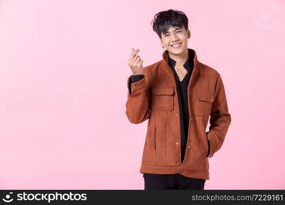 Asian a man handsome young smiling happy showing mini heart or heart-shaped hands gesture and the side eyes looking at camera in love isolated on pink blank copy space studio background.