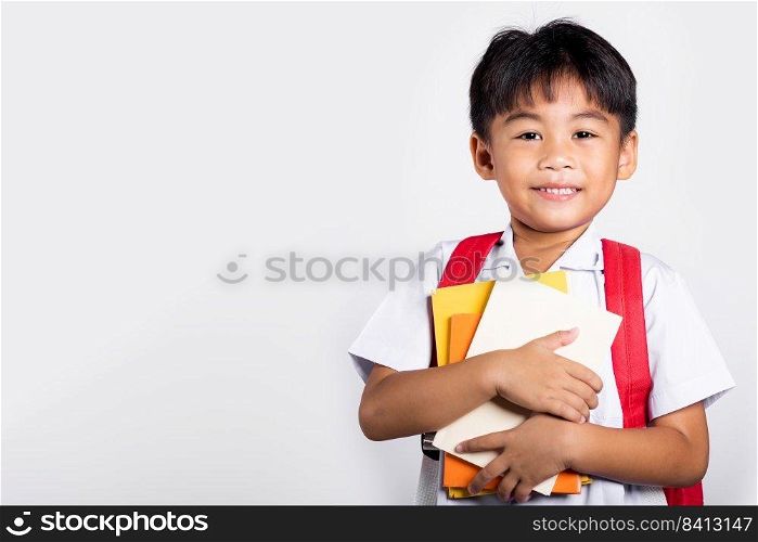 Asian adorable toddler smiling happy wear student thai uniform red pants stand hold or hugging book in studio shot isolated on white background, Portrait little children boy preschool, Back to school