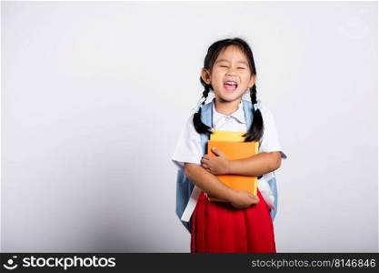 Asian adorable toddler smiling happy wear student thai uniform red skirt stand hold or hugging book in studio shot isolated on white background, Portrait little children girl preschool, Back to school