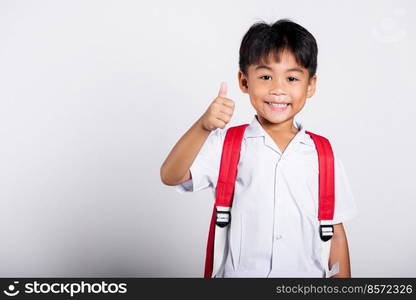 Asian adorable toddler smiling happy wearing student thai uniform red pants show thumb up finger in studio shot isolated on white background, Portrait little children boy preschool, Kid Back to school