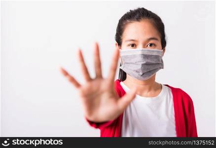 Asian adult woman wearing red shirt and face mask protective against coronavirus or COVID-19 virus or filter dust, air pollution her raise palm hand to no or stop sign, isolated white background