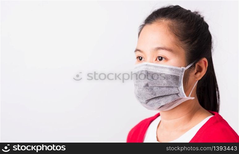 Asian adult woman wearing red shirt and face mask protective against coronavirus or COVID-19 virus or filter dust pm2.5 and air pollution she looking side, studio shot isolated white background