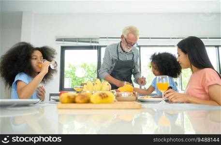 Asian-African American family Have a happy meal together which includes grandfather, mother and children in the dining room of the house.