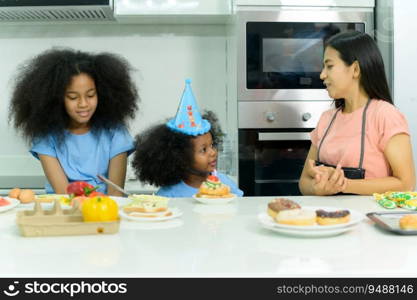 Asian-African American family Organize a birthday party for little sister in the kitchen of the house.