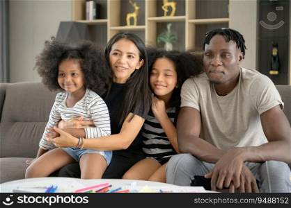 Asian-African American family relaxing, chatting, painting and having fun on vacation in the living room of the house