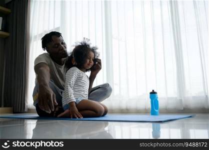 Asian-African American father and son relaxing and listening to music together after yoga exercise in the living room of the house.