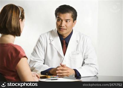 Asian American male doctor consulting with Caucasian female patient.