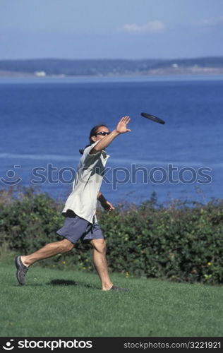 Asian American Man Catching A Frisbee Near A Lake
