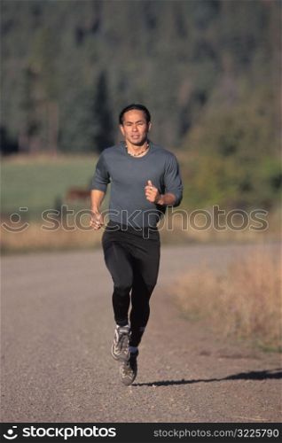 Asian American Man Jogging Through The Countryside On A Dirt Road
