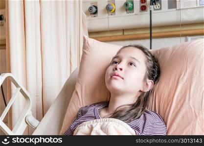Asian American tween girl lying in hospital bed, health care concept