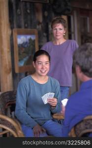 Asian American Woman Sitting In A Cabin And Playing Cards With Friends