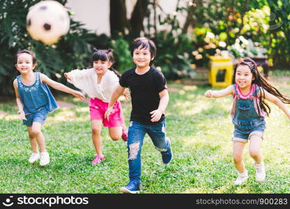Asian and mixed race happy young kids running playing football together in garden. Multi-ethnic children group, outdoor sport exercising, leisure game activity, or childhood fun lifestyle concept