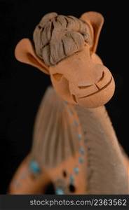 Asian and Oriental painted toy from burnt clay in the form of a camel on a black background. colored toy from clay