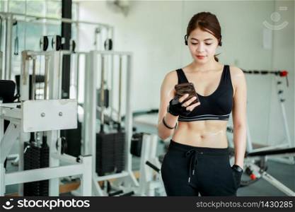Asian athlete in sportswear fashion clothing. Sportswoman listening to music using phone app for fitness activity tracker - heart rate monitor tracking her health progress on smartphone.