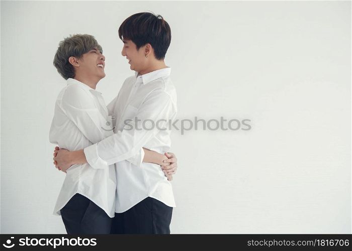 Asian attractive LGBT young gay couple hugging looking at each other and kissing in the room on white background