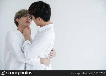 Asian attractive LGBT young gay couple hugging looking at each other and kissing in the room on white background