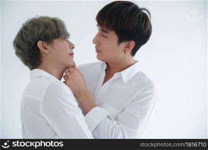Asian attractive LGBT young gay couple hugging looking each other and kissing in room on white background