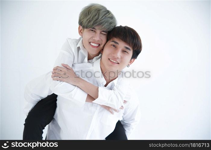 Asian attractive LGBT young Gay Couple riding on back and hugging in room on white background