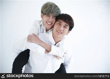 Asian attractive LGBT young Gay Couple riding on back and hugging in room on white background