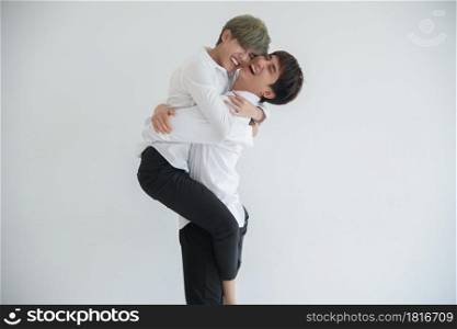 Asian attractive LGBT young gay couple riding on front and hugging kissing each other in the room on white background