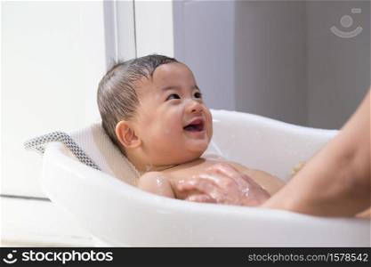 Asian baby boy taking a bath by mom. Hygiene and care for young children concept