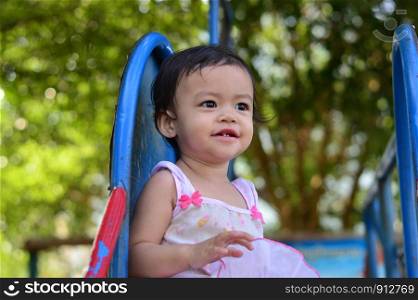Asian baby girl on slider at playground