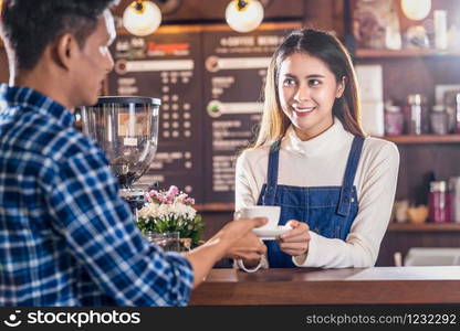 Asian Barista of Small business owner serving a cup of coffee to young customer at the coffee counter in coffee shop, Small business owner and startup in coffee shop and restaurant concept