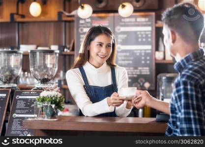 Asian Barista of Small business owner serving a cup of coffee to young customer at the coffee counter in coffee shop, Small business owner and startup in coffee shop and restaurant concept