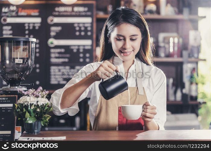 Asian Barista preparing cup of coffee, espresso with latte or cappuccino for customer order in coffee shop,bartender pouring milk,Small business owner and startup in coffee shop and restaurant concept