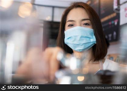 Asian barista women wearing face masks to prevent contagious diseases and serve customers in the coffee shop. The concept of prevention from COVID 19