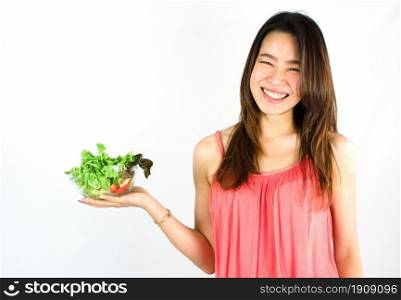 Asian beautiful and healthy woman smiling with happiness, presenting a dish of vegetable and standing on white background