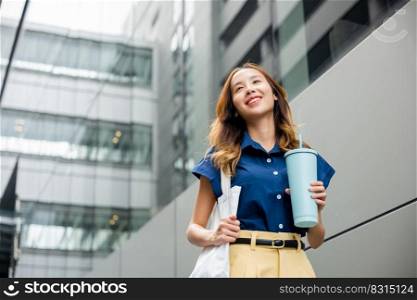Asian beautiful business woman confident smiling with cloth bag holding steel thermos tumbler mug water glass she walking outdoors on street near modern building office, Happy female looking side away