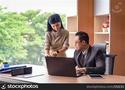 asian beautiful secretary helping boss, showing information from tablet, in office