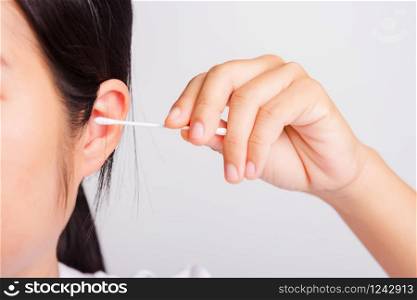 Asian beautiful woman cleaning ear hrt using cotton swab on white background with copy spece for text, healthcare concept