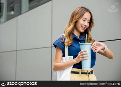Asian beautiful woman confident smiling with cloth bag holding steel thermos tumbler mug water glass she walking outdoors on street near modern building office, Happy female looking watch time