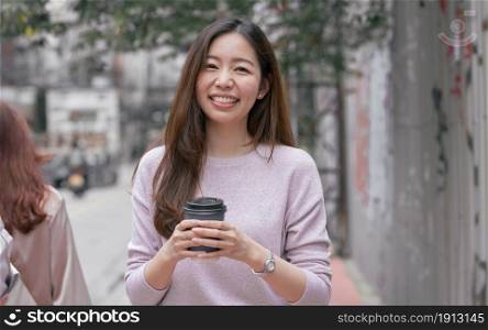 Asian beautiful woman drinking coffee while walking beside the street in winter season. Lifestyle Concept.