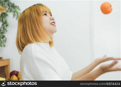 Asian beautiful woman eat orange in the kitchen at her home. Happy pretty asian female eat freshness fruit for healthy body. lifestyle asia woman at home concept.