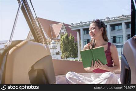 Asian beautiful woman reading book while traveling and sitting on boat with background of beautiful lanscape. Summer Travel and Lifestyle Concept.