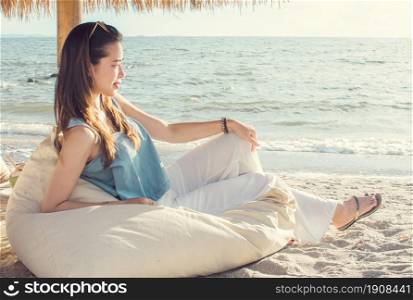 Asian beautiful woman sitting and being relax beside the beach and sea while traveling on summer trip