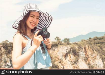 Asian beautiful woman smiling and taking photo while traveling on summer trip with blur background of mountaints and blue sky