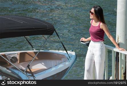 Asian beautiful woman wearing sunglasses and waiting for a boat at port near the river. Travel and Lifestyle concept.