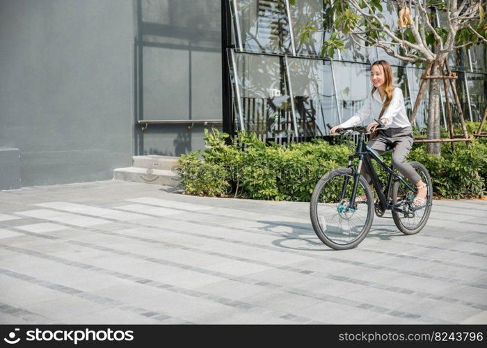 Asian beautiful young businesswoman with helmet riding bicycle go to office work at city street with bicycle in morning, Happy lifestyle woman bike after business work outside building , Eco friendly