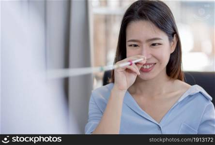 Asian beautiful young woman smiling and doing eye test in optical lab