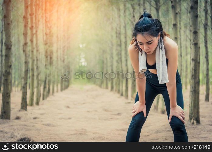 Asian beauty woman tiring from jogging in forest. Towel and sweat elements. Sport and Healthy concept. Jogging and Running concept. Relax and take a break theme. Outdoors activity theme.